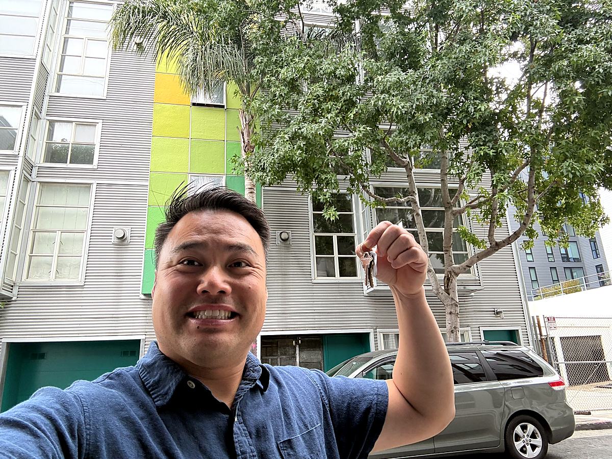 Kevin Choy holding keys outside 281 Clara Street on closing day